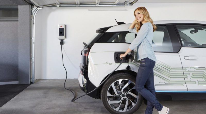 mulher carregando o carro elétrico na tomada
